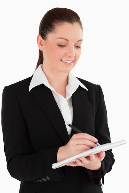 Portrait of a gorgeous woman in suit writing on a notebook