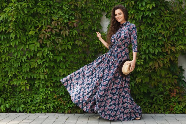 Photo portrait of gorgeous woman wearing beautiful maxi dress posing against wall with a wild grape