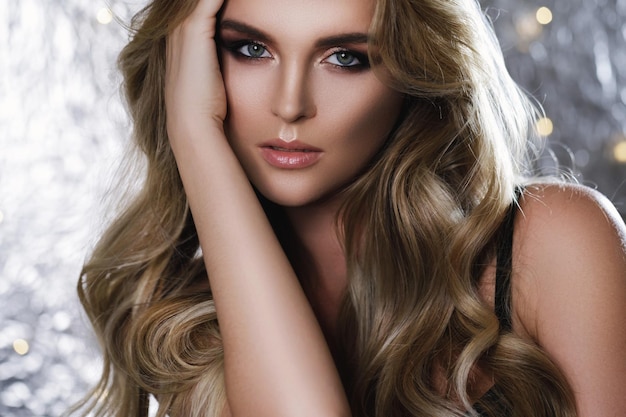 Photo portrait of gorgeous woman with a beautiful curly hair and professional makeup in studio