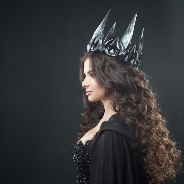 ゴシックプリンセスの肖像画。金属の王冠と黒いマントで美しい若いブルネットの女性。