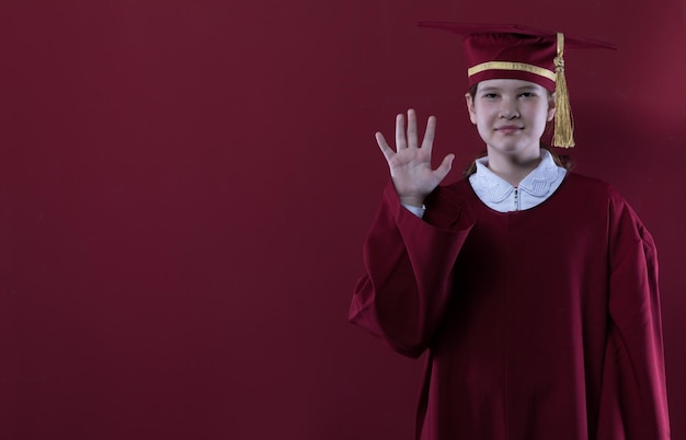 portrait of a graduate girl in a graduation cap on a red background