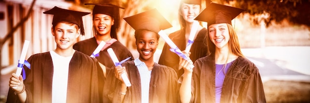 Portrait of graduate school kids standing with degree scroll in
campus