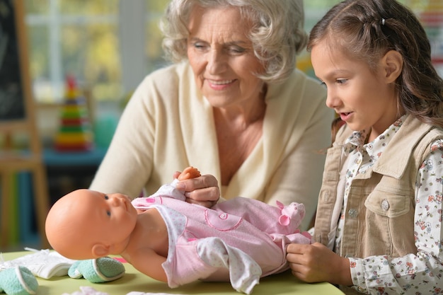 Portrait of grandmother and child play with baby doll