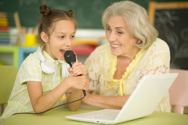 Portrait of grandmother and daughter singing karaoke with laptop