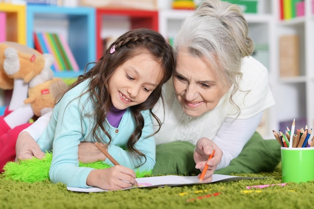 Portrait of grandmother and granddaughter drawing at home