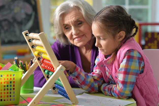 Portrait of grandmother and granddaughter do homework at home