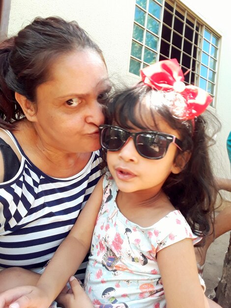 Photo portrait of grandmother kissing granddaughter outdoors