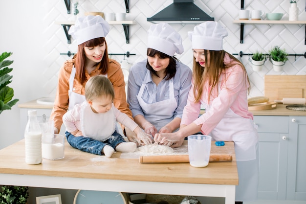 Portrait of Grandmother with her daughters and granddaughter together making dinner at the kitchen. Mothers Day concept.