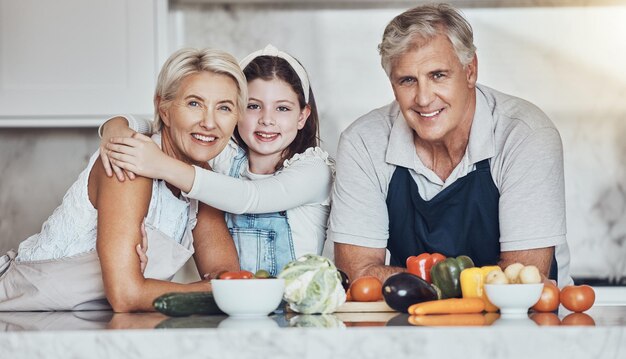 저녁 식사를 위해 유기농 야채를 곁들인 집 부엌에서 행복한 가족으로 요리하는 초상화 조부모나 소녀