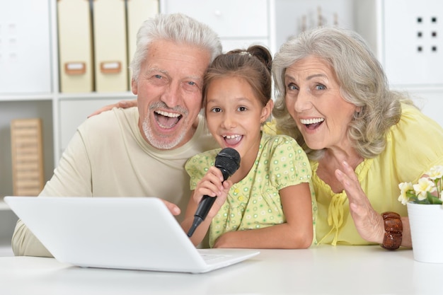그녀의 손녀가 집에서 태블릿으로 노래방을 부르고 있는 조부모의 초상화