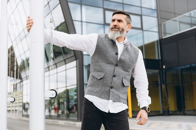 Portrait of a gray bearded and brutal man spending time on the urban space