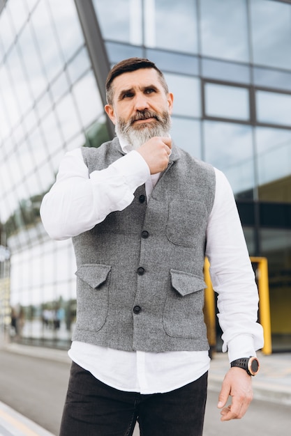 Portrait of a gray bearded and brutal man spending time on the urban space