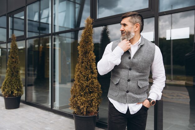 Portrait of a gray bearded and brutal man spending time on the urban space