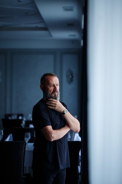 Portrait of a gray-haired adult successful man with a serious face in a black t-shirt