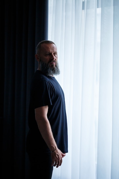 Portrait of a gray-haired adult successful man with a serious face in a black t-shirt