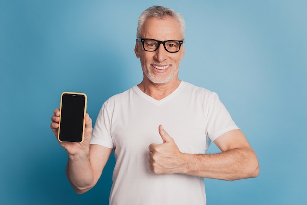 Portrait of gray-haired old man using cell phone internet thumb-up show