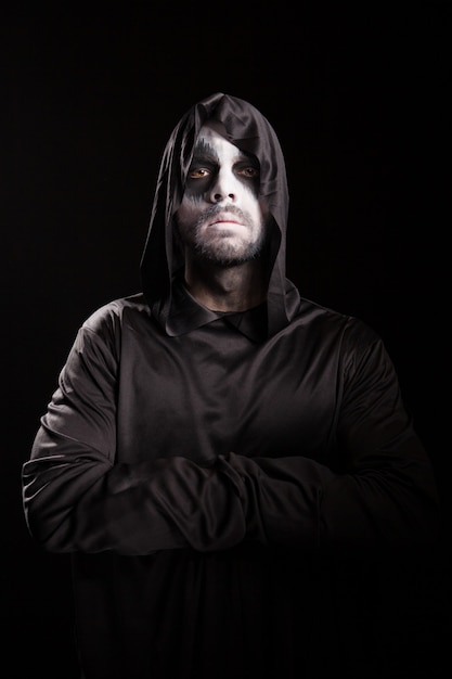 Foto ritratto di grim reaper con le mani incrociate isolate su sfondo nero. costume di halloween.