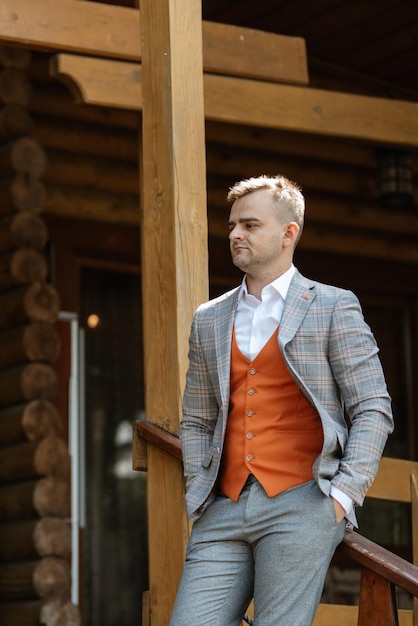 Portrait of the groom in a gray suit and an orange vest