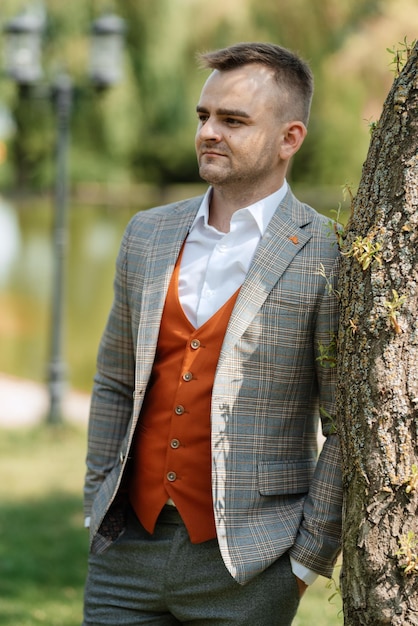 Portrait of the groom in a gray suit and an orange vest