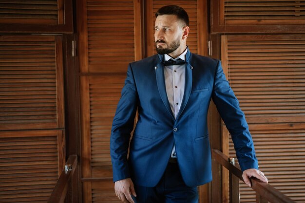 Portrait of a groom with a beard in a blue suit