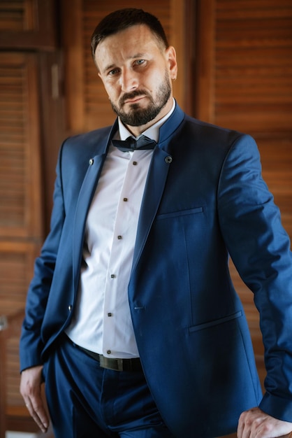 Portrait of a groom with a beard in a blue suit