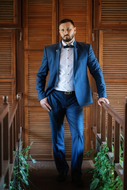 Portrait of a groom with a beard in a blue suit