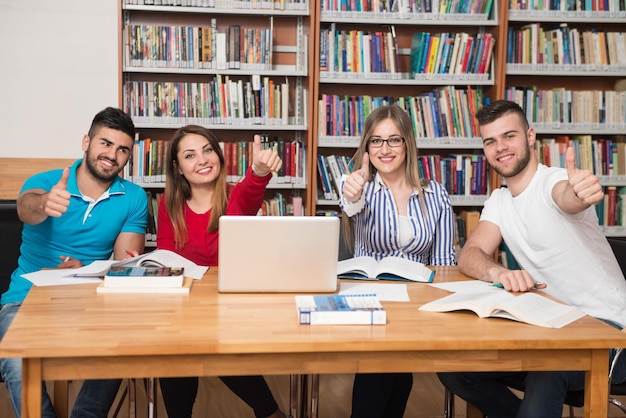 Portrait Of A Group Of Students Showing Thumbs Up In College Library  Shallow Depth Of Field