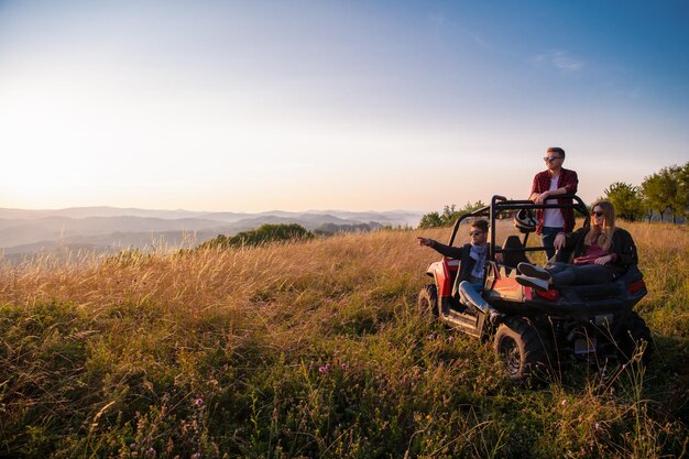 portrait of group young happy people enjoying beautiful sunny day while driving a off road buggy car on mountain nature