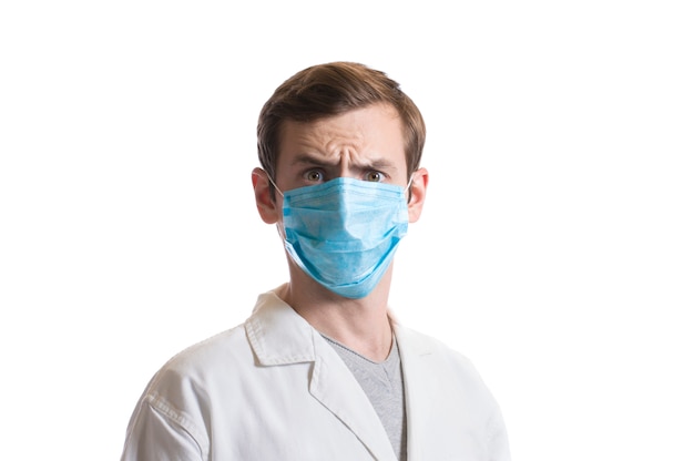 Portrait of a guy in a disposable mask and a medical coat on a white