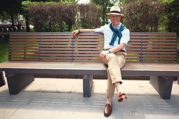 Портрет парня, сидящего на скамейке в парке