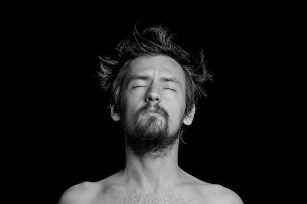 Portrait of a guy with a beard and tousled hair on a black background