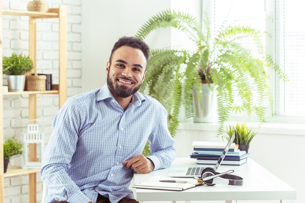 Portrait of handsome African black young business man working on laptop at office