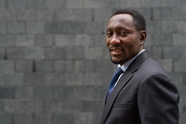 Portrait of handsome African businessman in city smiling