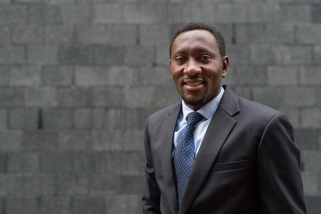 Portrait of handsome African businessman in city smiling