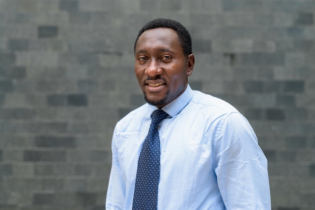 Portrait of handsome African businessman in city smiling