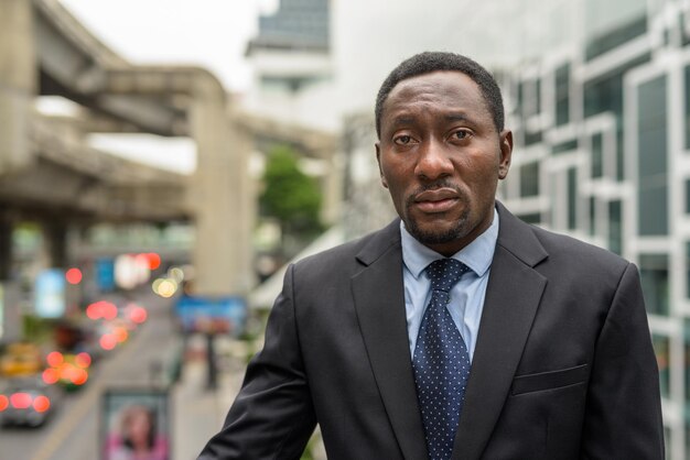 Portrait of handsome African businessman outdoors in city