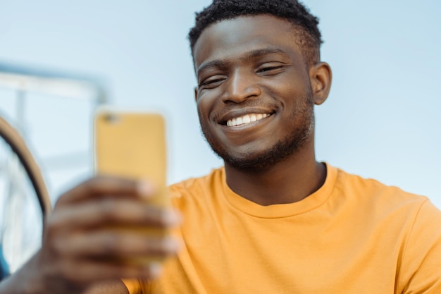 Portrait of handsome african man holding mobile phone outdoors on street