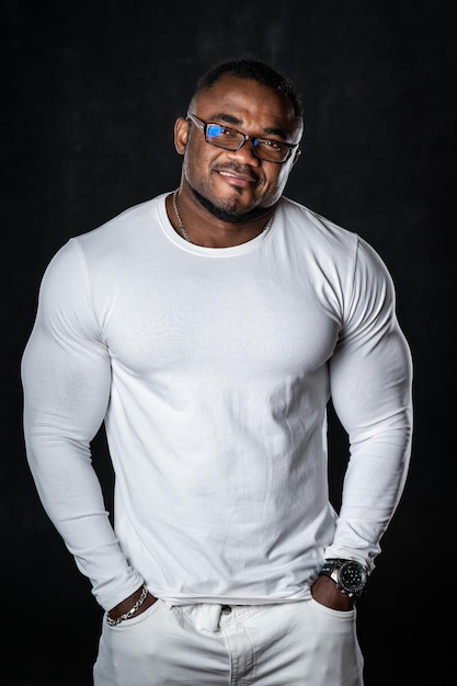 Portrait of a handsome afro american fitness model man. Bodybuilder in total white look shows strong body.
