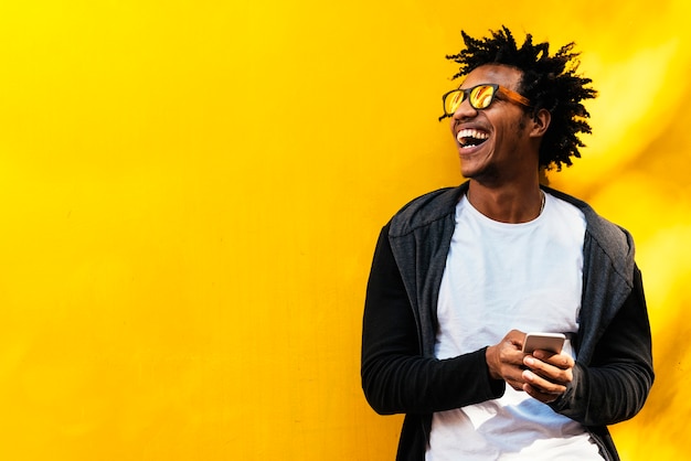 Portrait of handsome afro man using his mobile in the street