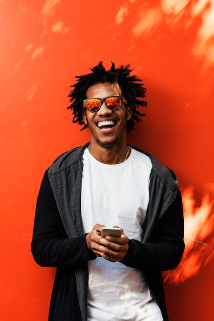 Portrait of handsome afro man using his mobile in the street.