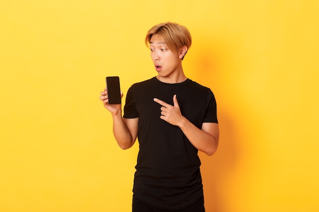 Portrait of handsome asian man showing something on smartphone screen