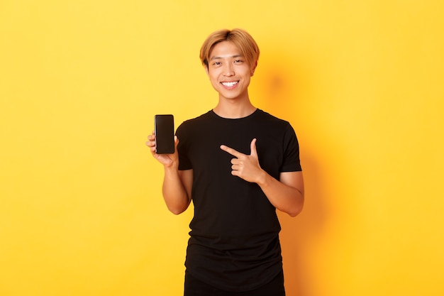 Portrait of handsome asian man showing something on smartphone screen