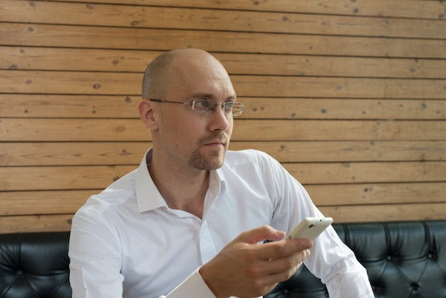 Portrait of handsome bald businessman with beard stubble against wooden wall indoors