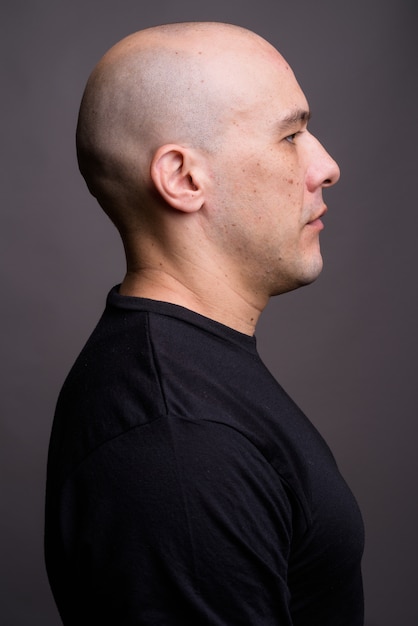 Portrait of handsome bald man against gray background