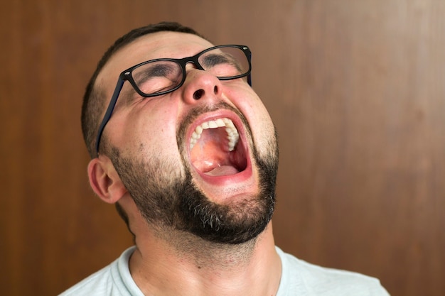 Ritratto di giovane moderno intelligente dai capelli neri barbuto bello in vetri con taglio di capelli corto e occhi neri gentili sorridenti su sfondo sfocato. concetto di gioventù e fiducia.