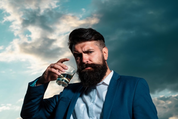 Portrait of a handsome bearded businessman in elegant suit drinking a whiskey