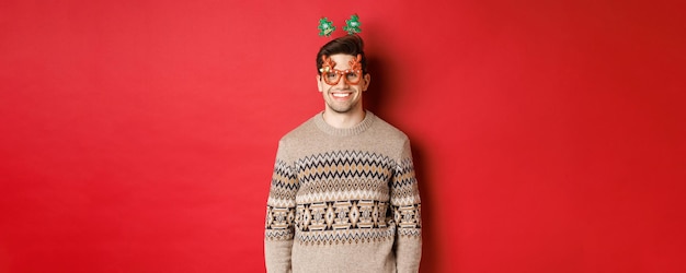 Photo portrait of handsome bearded guy in party glasses and winter sweater smiling pleased celebrating new...