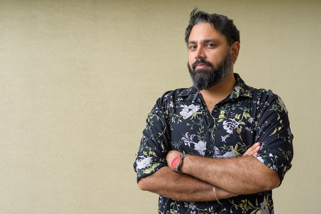 Portrait of handsome bearded Indian man against plain background