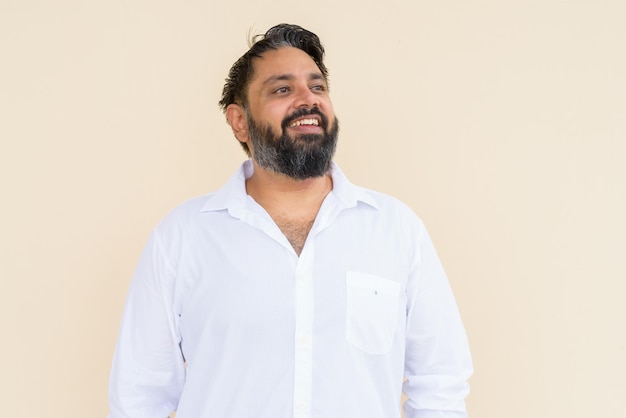 Portrait of handsome bearded Indian man against plain background