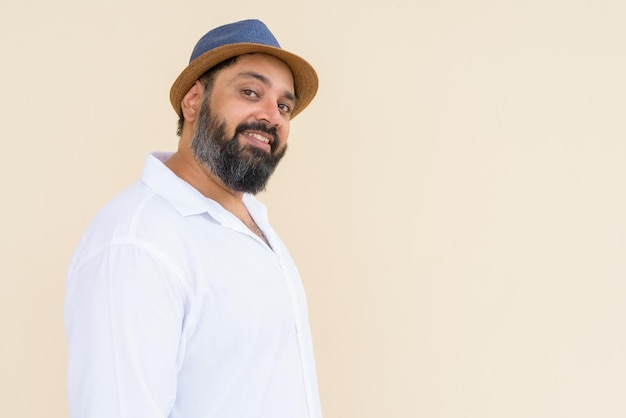 Portrait of handsome bearded Indian man against plain background